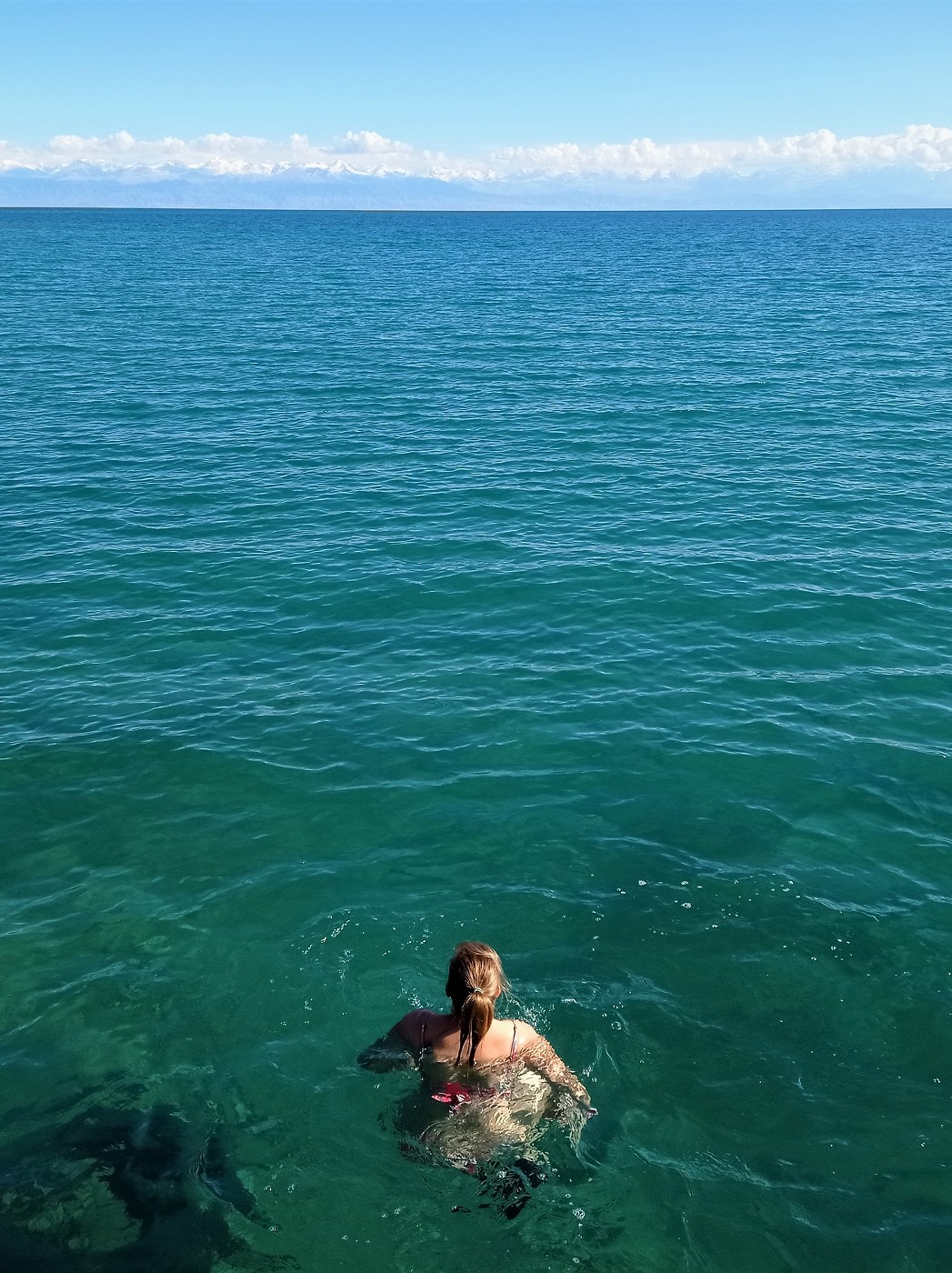 Swimming in Lake Issyk-Kul in Cholpon-Ata from a jetty snowcapped mountains