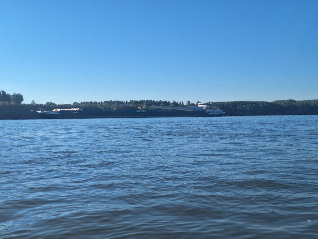 Danube river cargo ship with wing of a windmill wind power transportation international Europe inland shipping